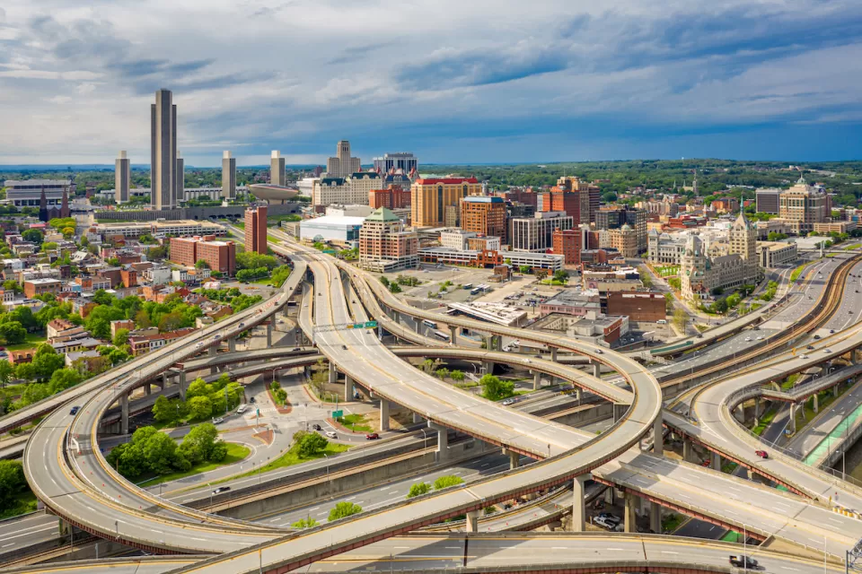 Aerial view of highways and downtown Albany skyline.
